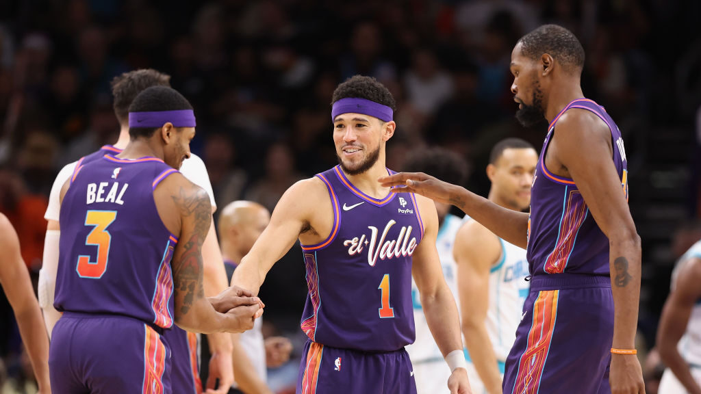 Devin Booker #1 of the Phoenix Suns celebrates with Bradley Beal #3 and Kevin Durant #35 after scor...